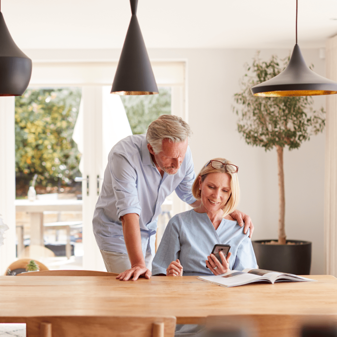 Couple at kitchen table looking at phone – 1